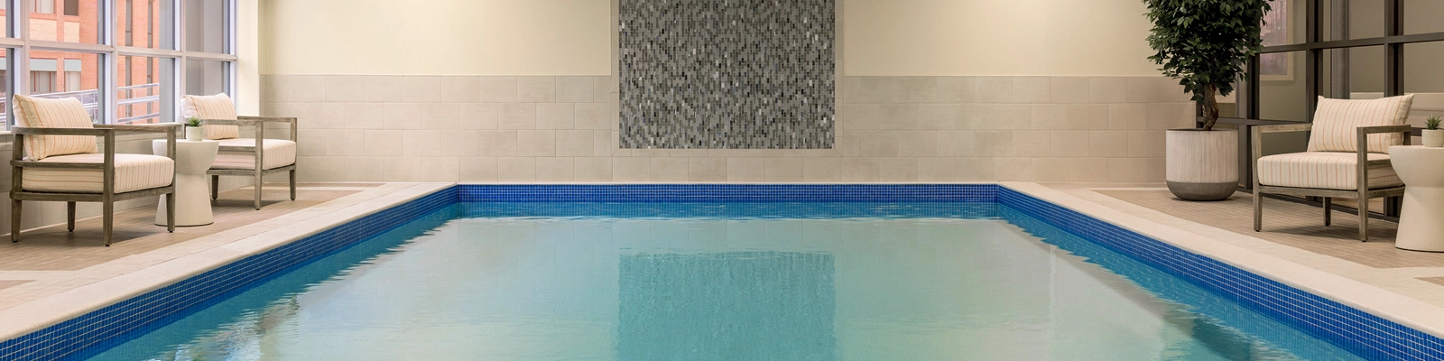 Unionville Pool with stone wall on one end and plush white pool chairs and greenery surrounding it.
