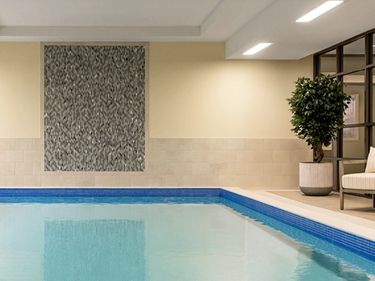 Unionville Pool with stone wall on one end and plush white pool chairs and greenery surrounding it.