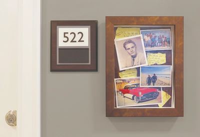 A memory care resident's suite door numbered 522 at Amica Kerrisdale, with a personalized shadow box frame displaying family photos and mementos