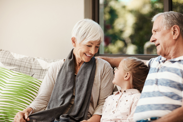 Senior couple sitting on sofa with a small girl.