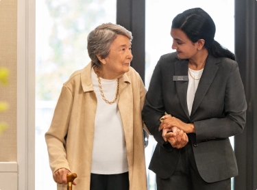 A senior walks arm-in-arm with an Amica employee.