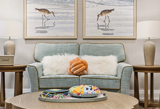 KER-Care Support Serenity Room A calm and softly decorated Serenity room at Amica Kerrisdale featuring a sofa with cushions, bird artwork on the walls, and a round coffee table with sensory items