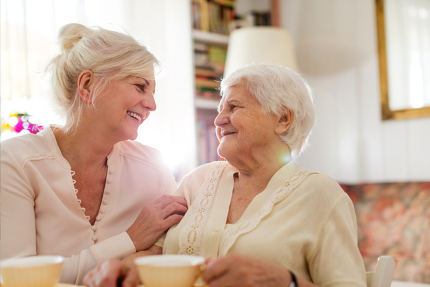 Senior woman drinking tea with a younger lady.