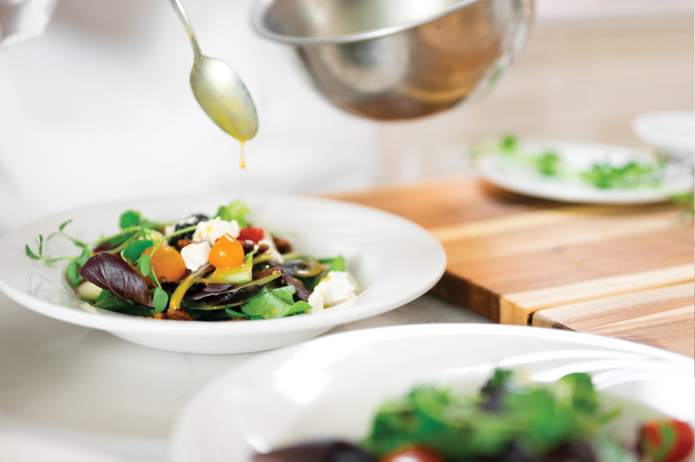 Chef drizzles dressing on salad Chef drizzles dressing on salad