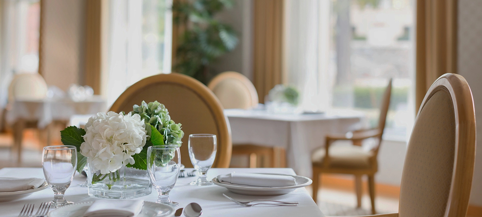 The West Vancouver dining room, with a close-up on a Square table with with chairs and a flower centrepiece.