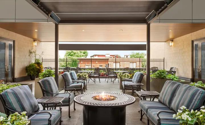 TheGlebe-home-outdoor_patio_with_chairs_and_fireplace_overlooking_greenery_and_surrounding_neighbourhood