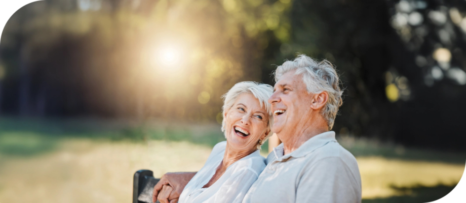 Senior couple sit on bench outside Senior couple sit on bench outside looking at each other and laughing.