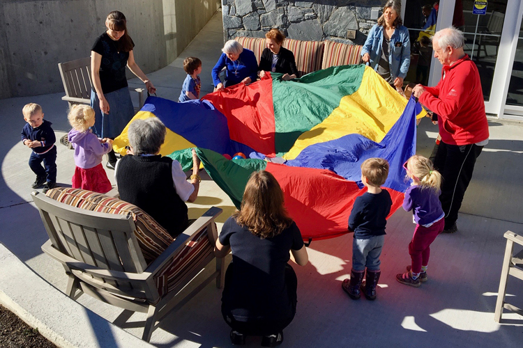 Amica residents playing a parachute activity with children on a patio