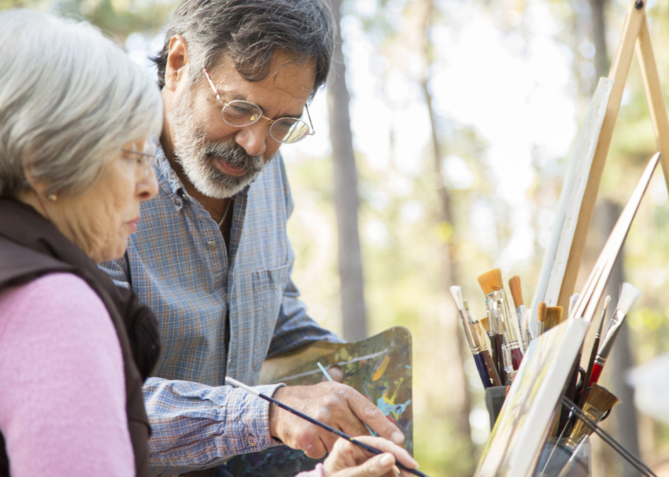 Active senior adult couple enjoys art hobby together outdoors in public park or forest area