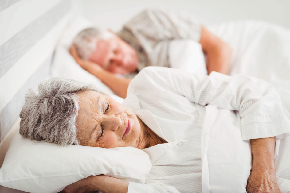 A senior woman and man asleep in bed