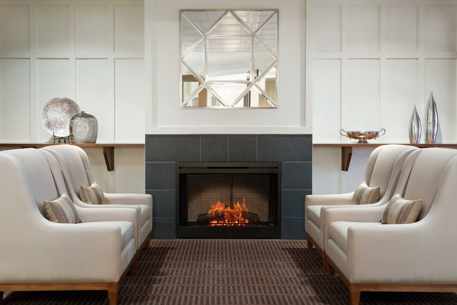 Amica London's Fireside Lounge: four beige armchairs facing one another next to a fireplace.