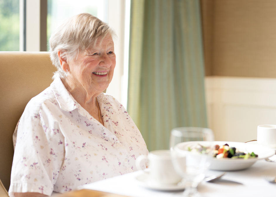 image of a resident sitting at the dining table with a plate of the Spring Salad in front of her