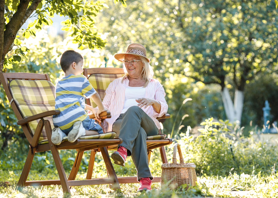 Grandmother sitting in garden and play with her grandson.