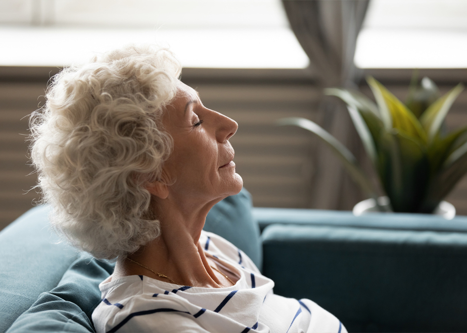 Side view close up face of a senior woman closed eyes enjoy fresh air spend time at home leaned on sofa, resting gaining mental and physical strength. Mindfulness meditation for seniors.