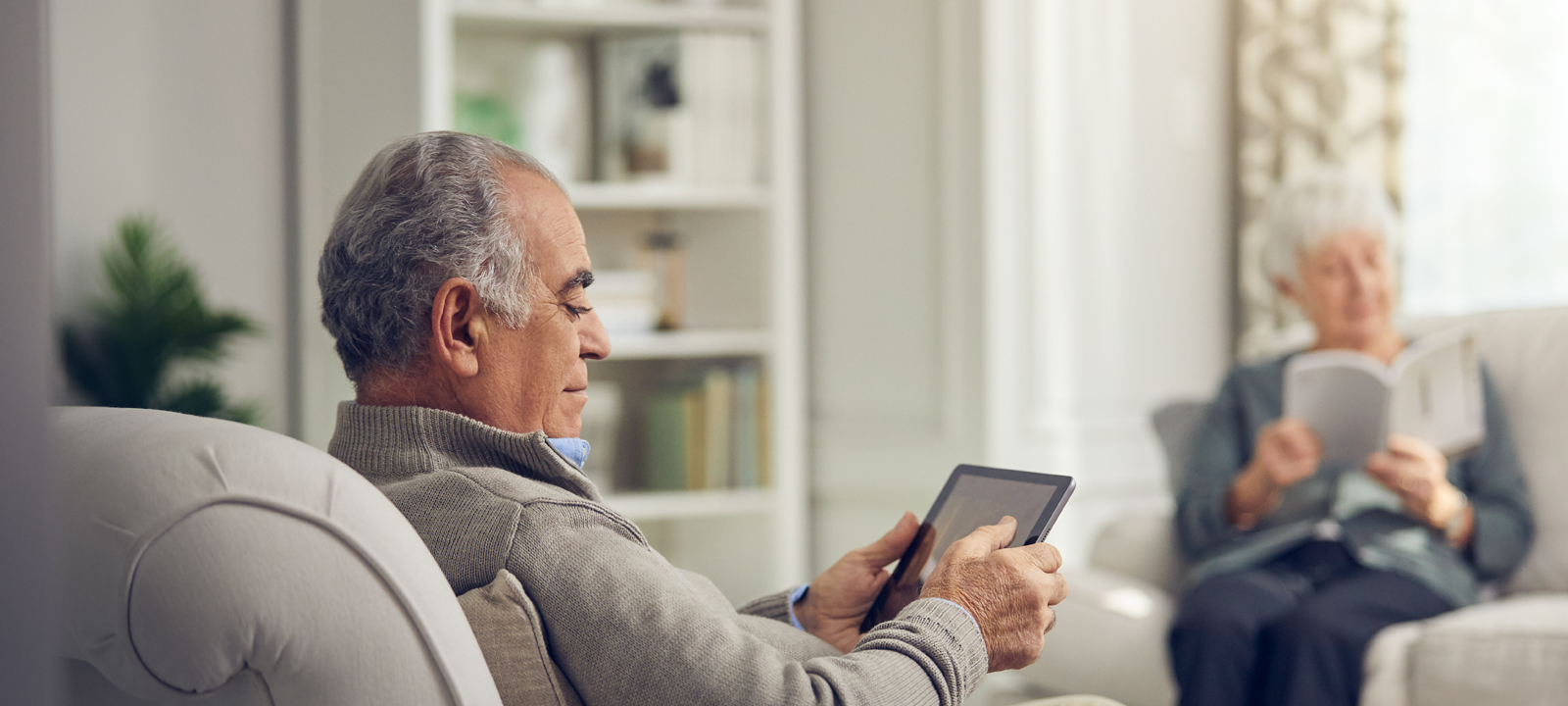 Male resident sitting in a comfortable chair using a tablet