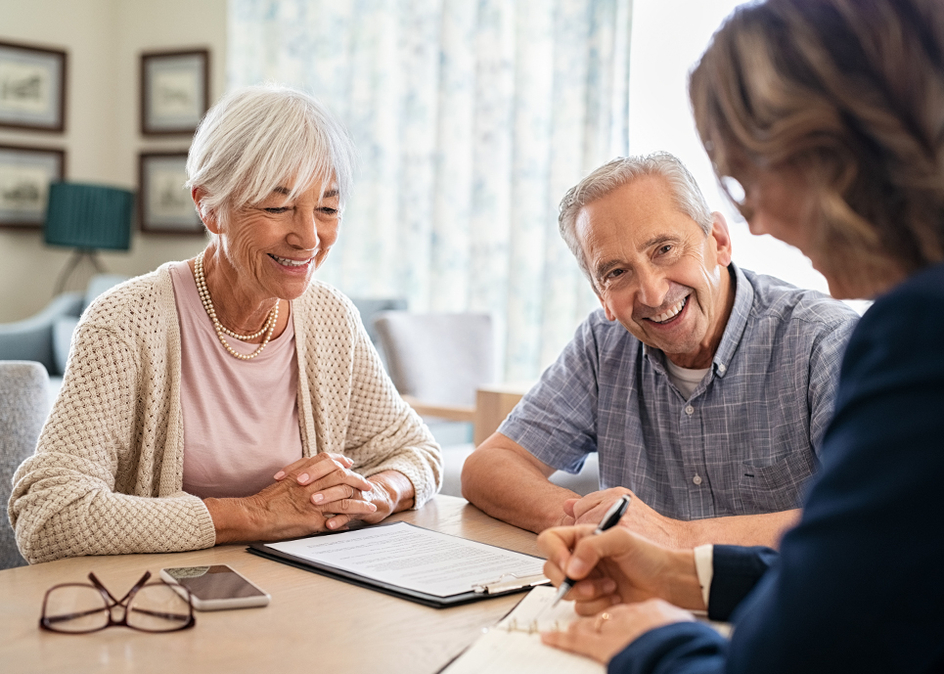 Senior couple planning their finances with an advisor in their home.