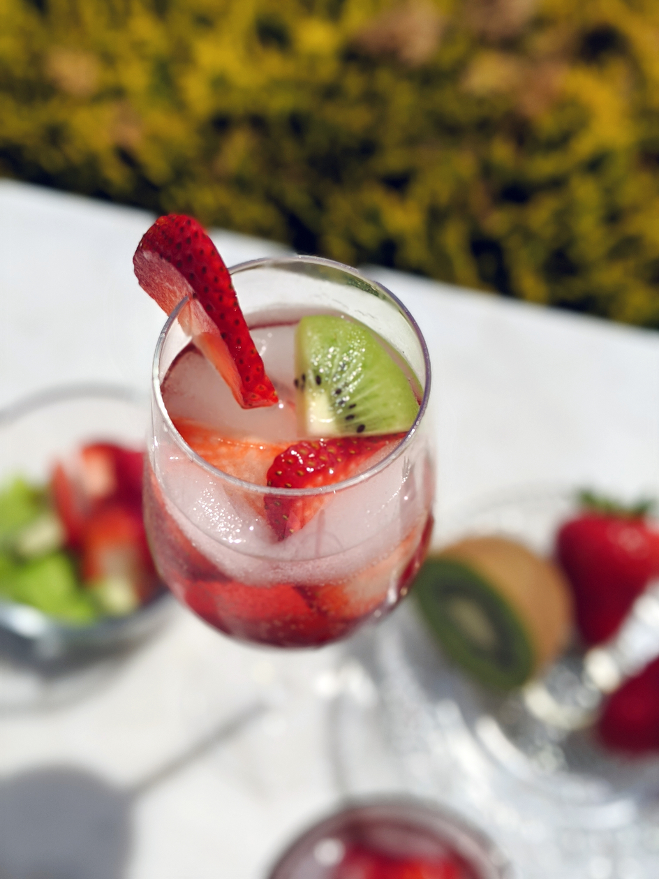 Strawberry Kiwi Hard Iced Tea Drink served in a glass-filled tumbler with fruit on an outdoor patio