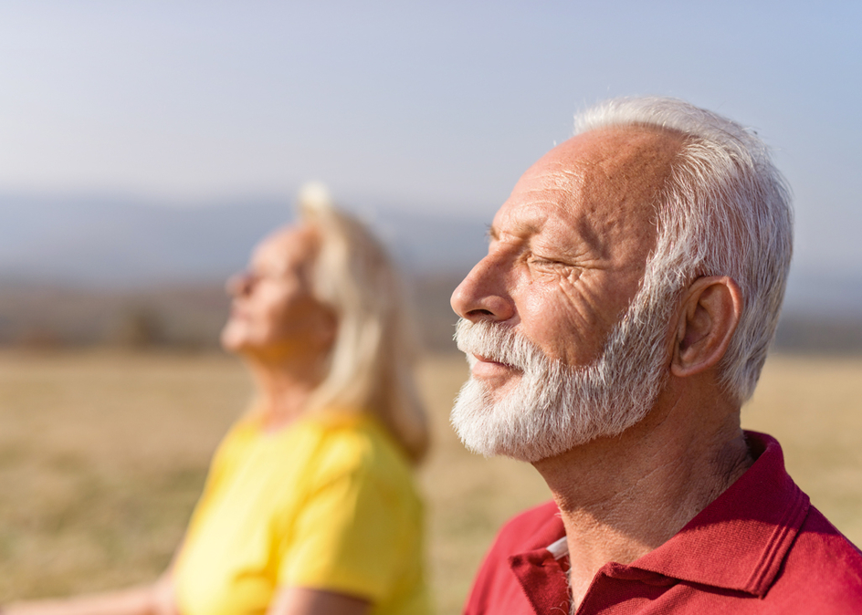 Relaxed senior man meditating in nature with his wife.