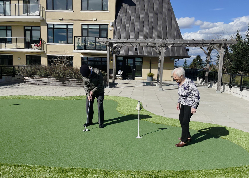 Two seniors playing golf outside on a sunny day.