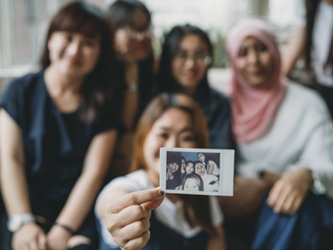 Multiethnic group of friends showing an instant print to the camera
