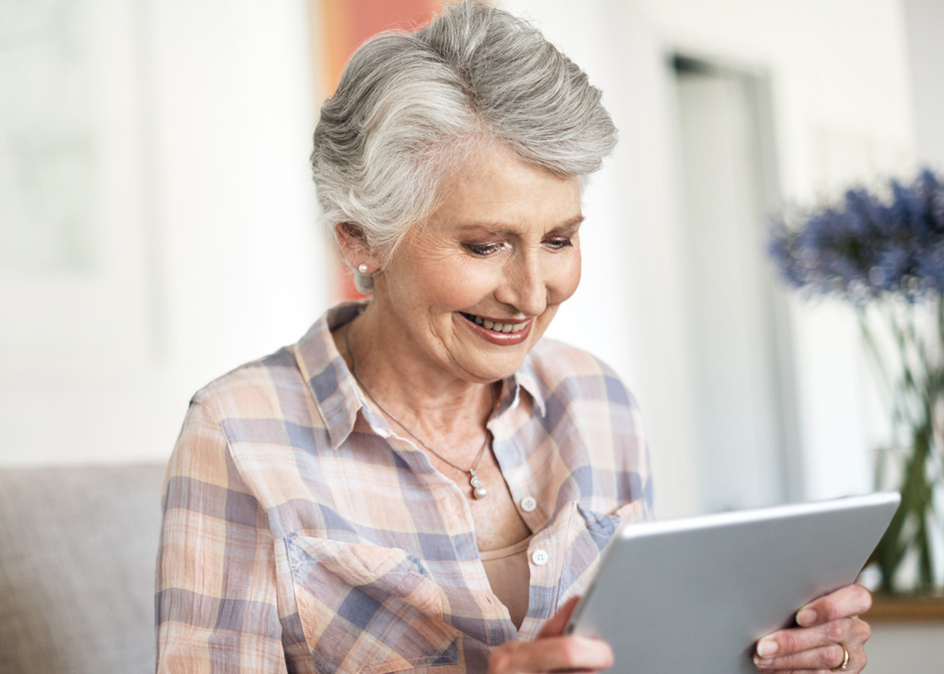 Shot of a happy mature woman using a tablet while relaxing in her lounge at home