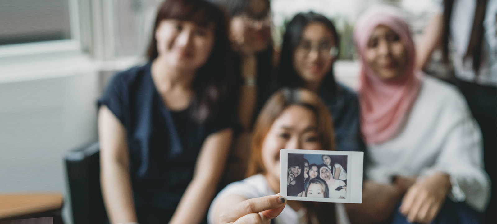 Multiethnic group of friends showing an instant print to the camera
