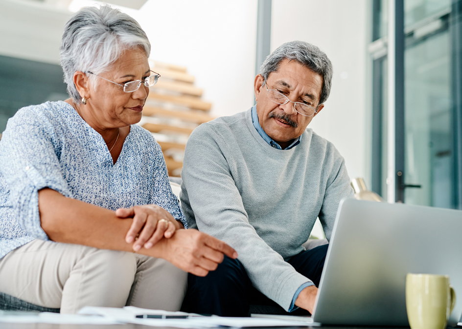 A senior couple using a laptop while sorting their finances together at home