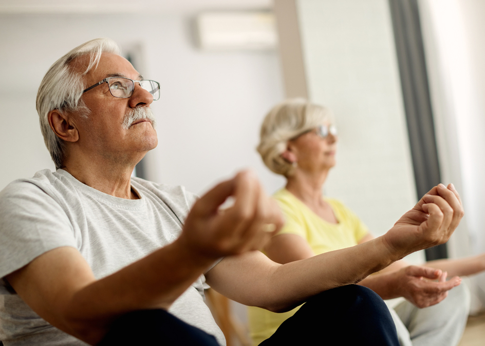 Senior couple in lotus position meditating at home.