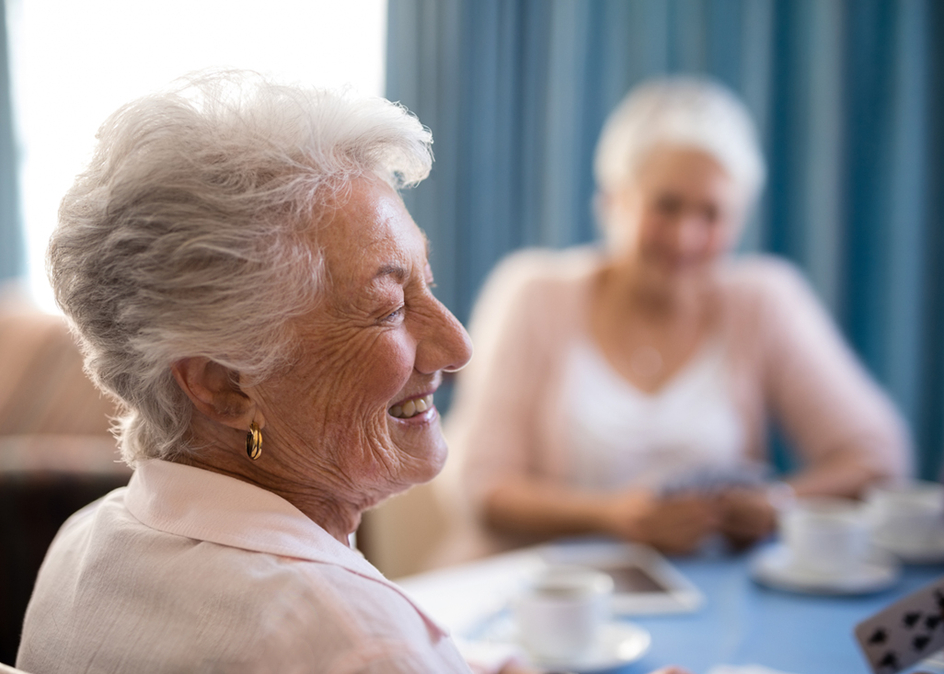 Happy Amica resident woman sitting with friends at table