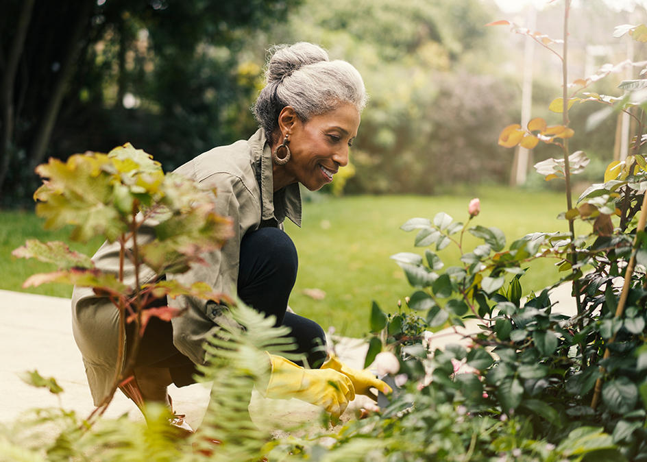 Side view of smiling senior woman taking care of a garden outside.
