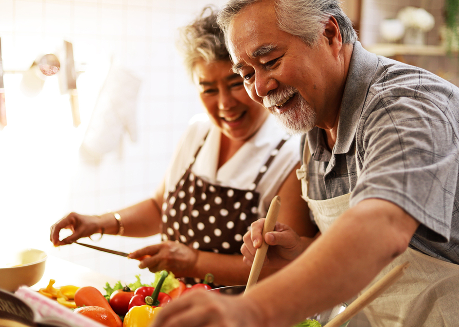 Senior elderly couple having fun in kitchen with healthy food