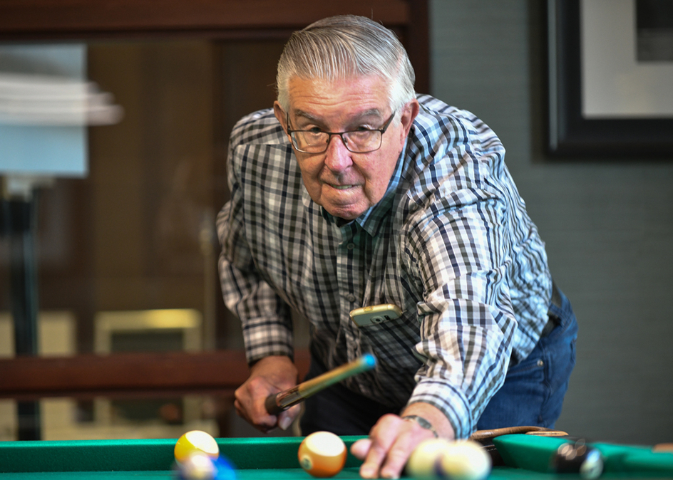 A senior resident playing billiards at an Amica residence