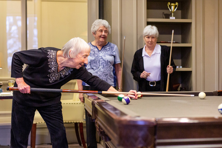 Three Amica residents playing a game of billiards together in the Games Room