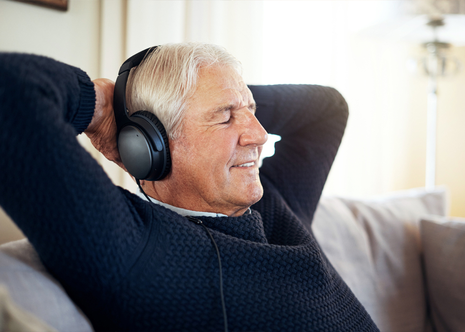 A Senior man listening to music with headphones on at home