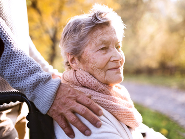 Senior man and woman in wheelchair in autumn nature.