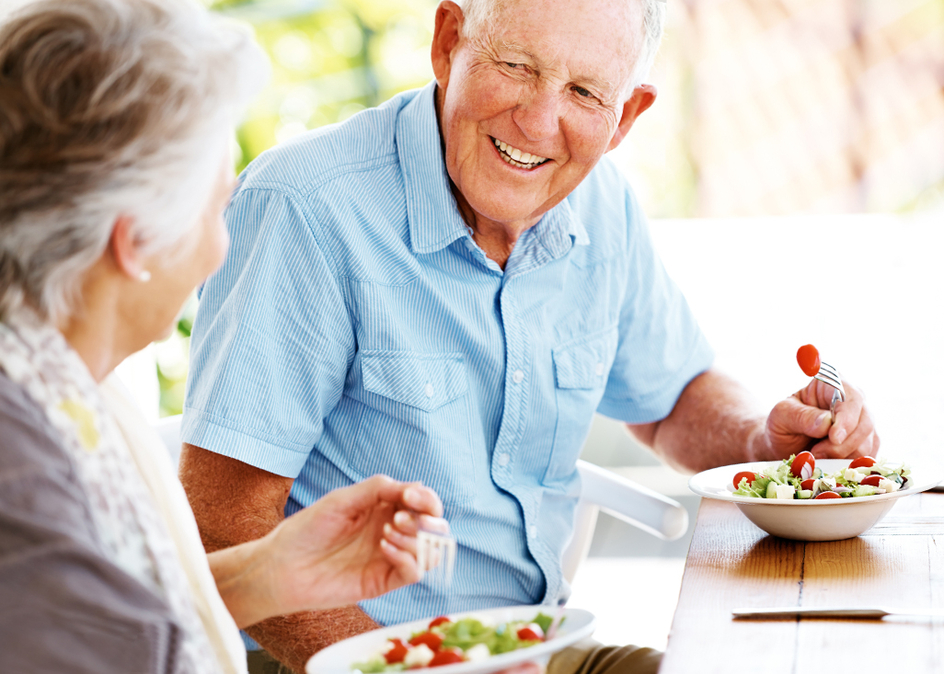 A happy senior couple relaxing together and enjoying a fresh salad