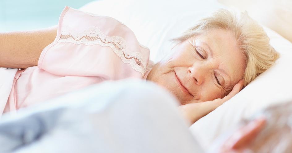 Senior woman with her eyes closed lying besides her husband in bed.