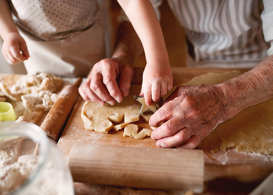 A senior and an adult making a pie together.